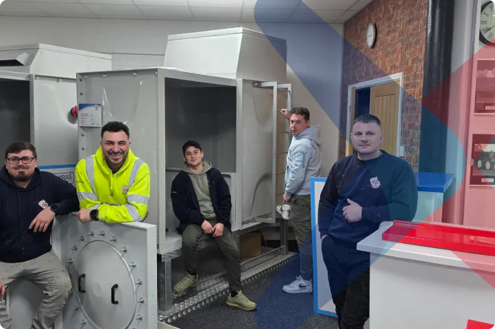 Team members posing with GRP water storage tanks in a workshop setting