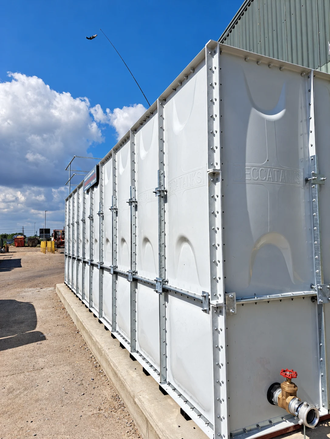 Outdoor sectional tank showing GRP panels, external fixings and a service valve