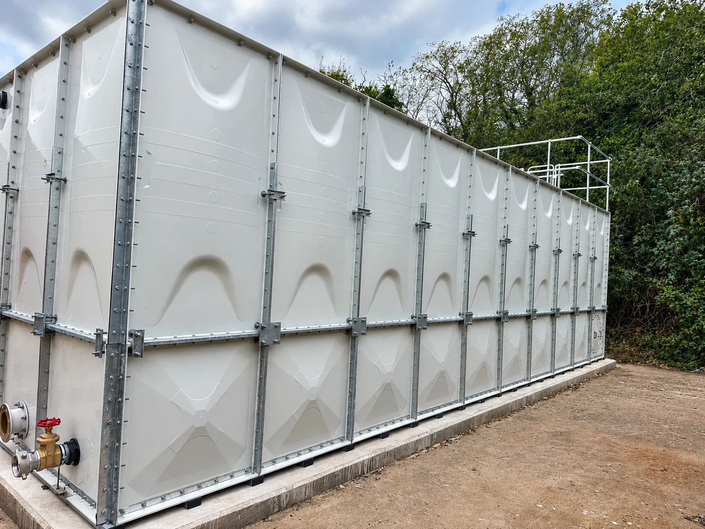 Long outdoor sectional water tank installation on a concrete plinth